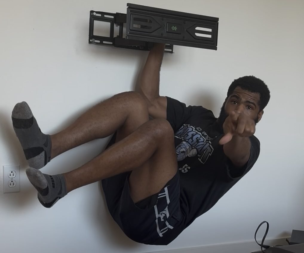 Ike hanging from a TV wall mount to demonstrate its holding strength